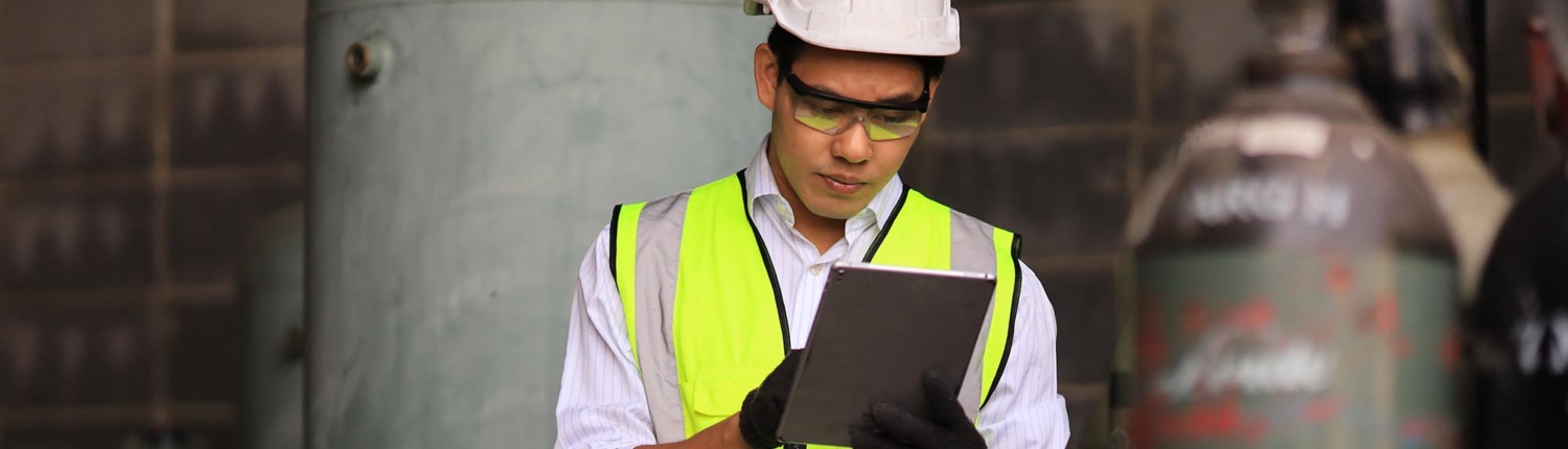 Industrial worker using a tablet to check on a large-scale coolant system